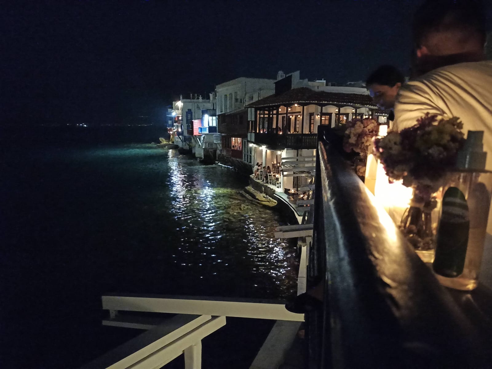 People having fun with night drinks on a balcony by the sea